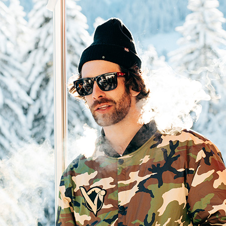 Man in the snow wearing Discord sunglasses with a black beanie. 